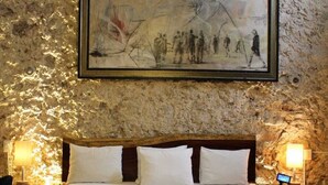 A bedroom with a large bed, a headboard, a bench, two bedside lamps, and a ceiling fan. - Hotel Zamna (Mérida)
