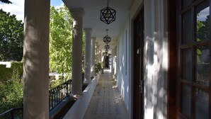A covered corridor with columns, patterned floor tiles, and hanging geometric light fixtures. - Hotel Zamna (Mérida)