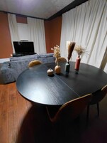 Una sala de estar moderna con una mesa redonda negra, un sofá y una televisión.