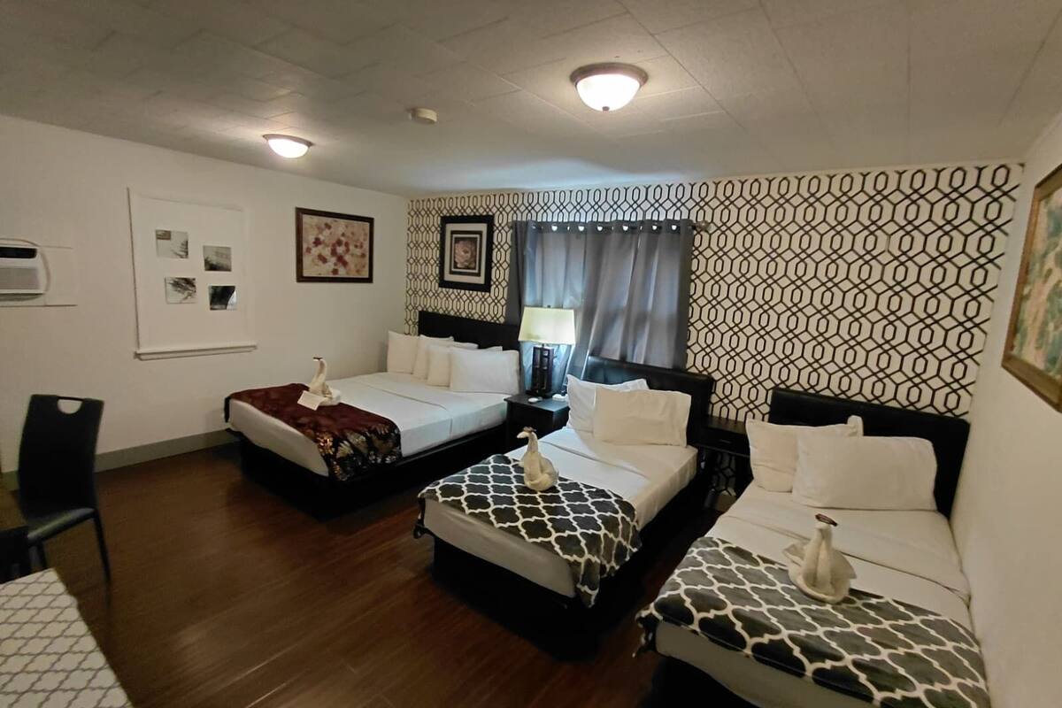 A hotel room with two beds, a desk, a chair, and a window with curtains.