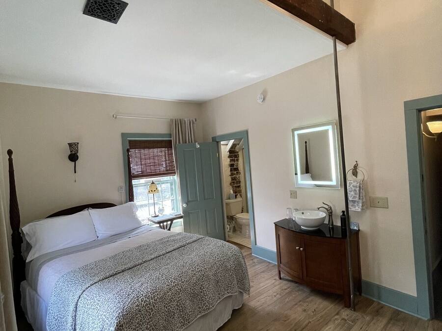 Un dormitorio con una cama, un tocador con espejo, piso de madera y ventilador de techo.