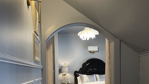 A bedroom with a bed, a nightstand, a lamp, and a chandelier. - Carriage House B&B (Winona)