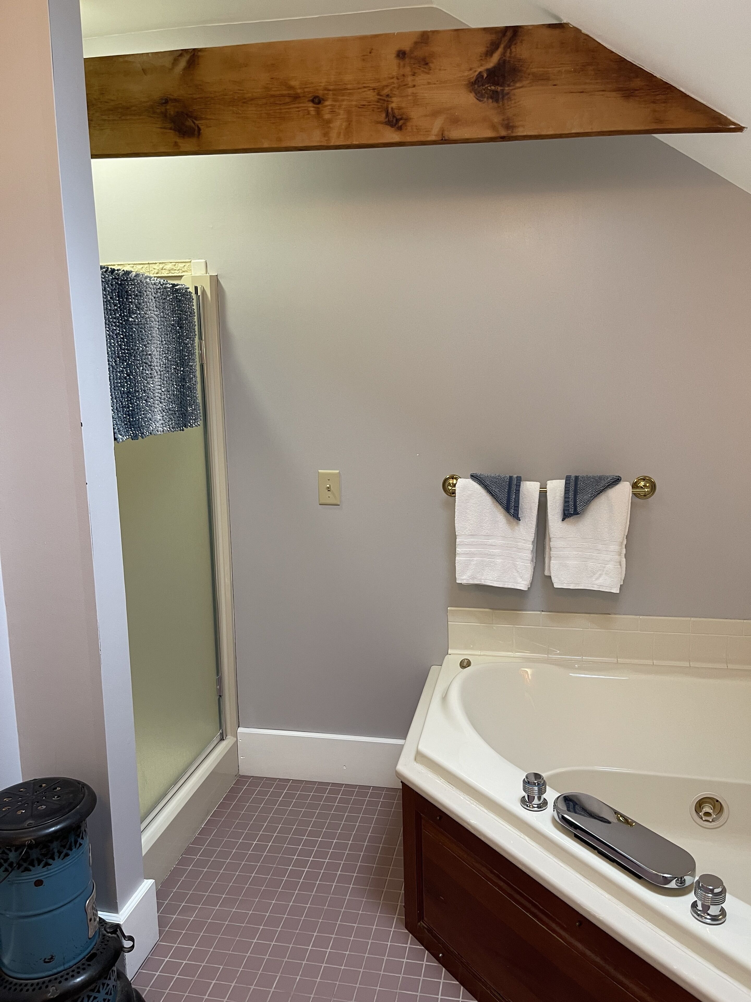 A bathroom with a shower, a bathtub, and two towels hanging on the wall.