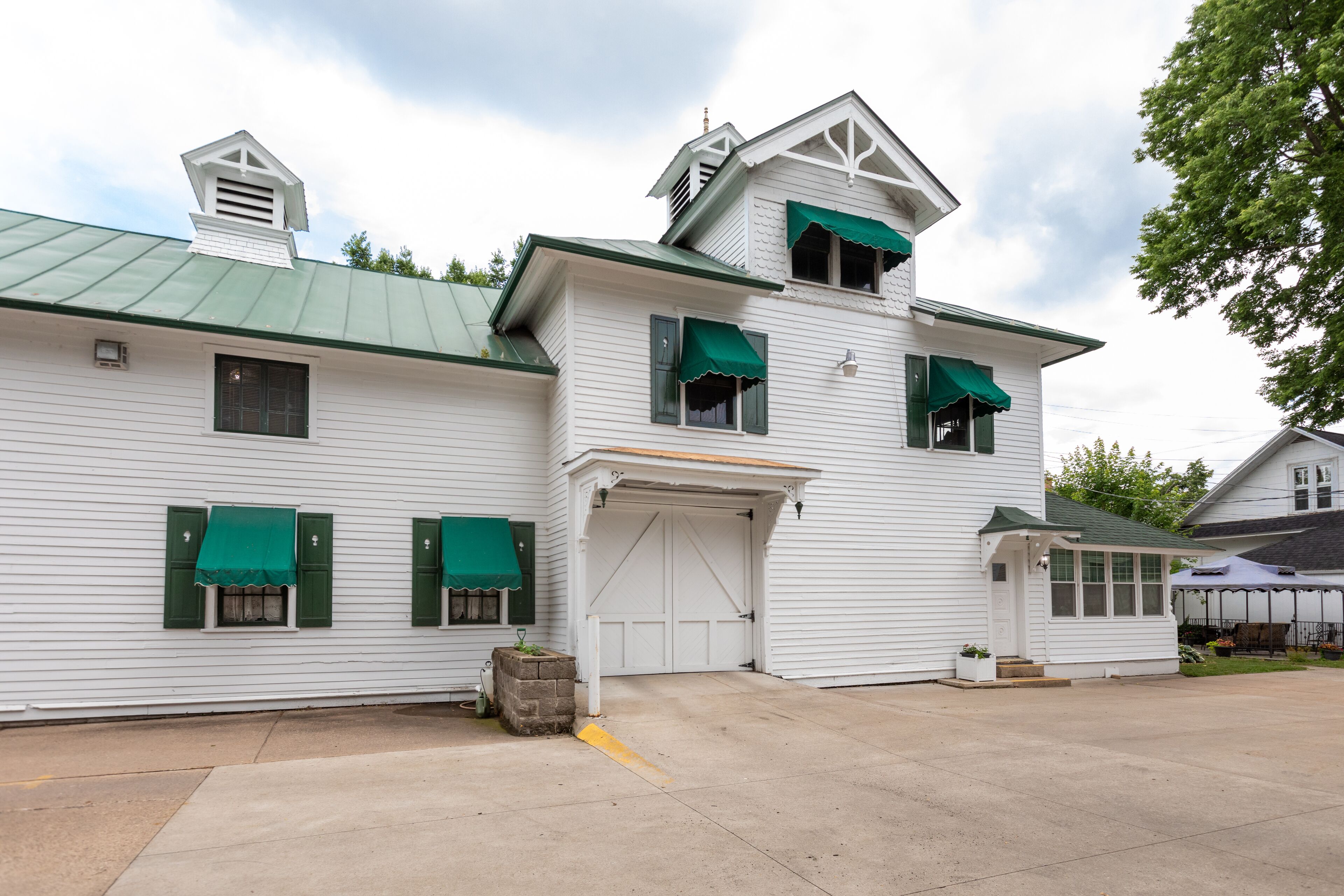 A white building with green shutters and a green roof.