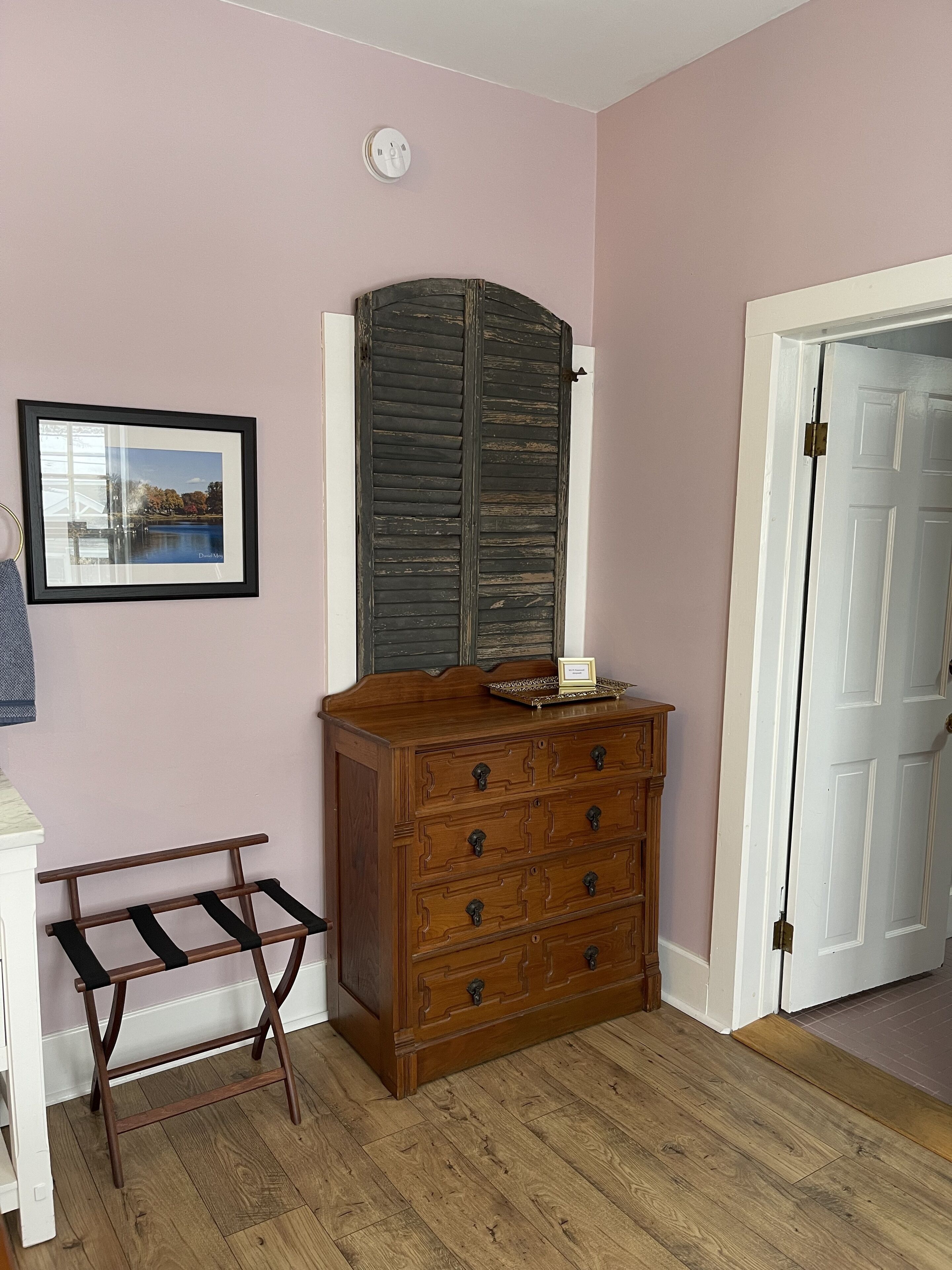 Een kamer met een houten dressoir, een lijst met een foto en een deur.