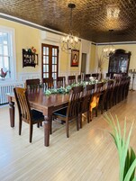 Comedor con una larga mesa de madera dispuesta para una comida, rodeada de sillas.