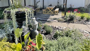 A garden with a pergola, a wooden table, and a variety of plants. - Carriage House B&B (Winona)
