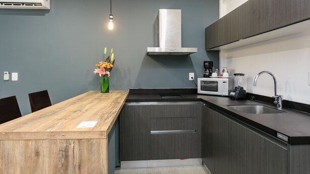 A modern kitchen with a wooden island, stainless steel appliances, and a grey backsplash. - Studio 30 Condhotel by Nah Hotels (Playa del Carmen)