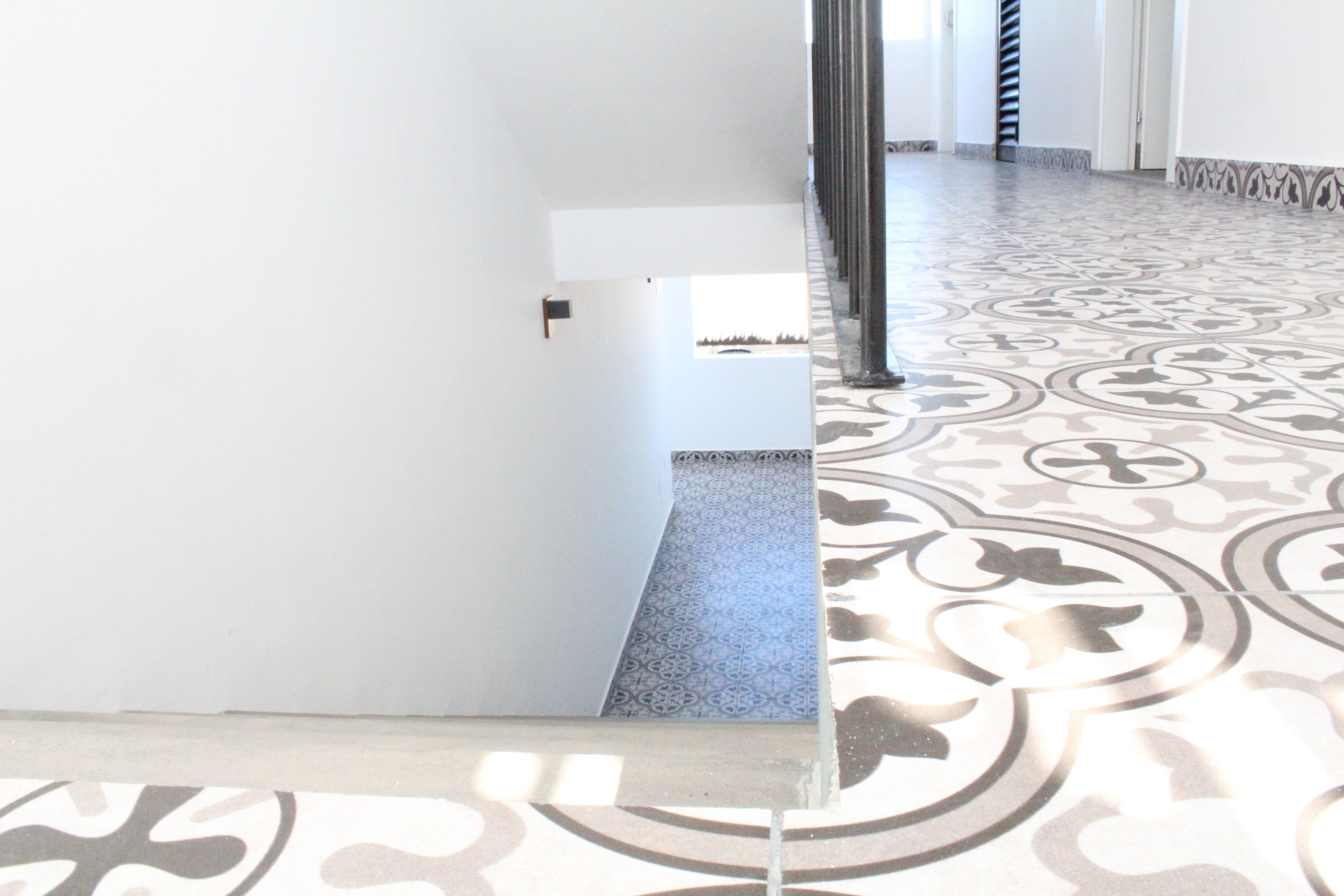 En hall med ett mönstrat golv och en vit vägg med en dörr.