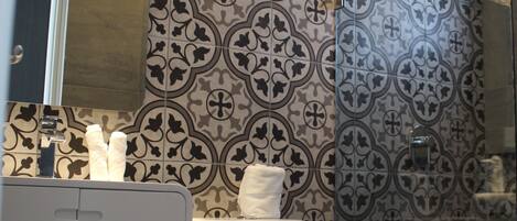 A bathroom with patterned tile walls, a white toilet, and a mirror above the sink.
