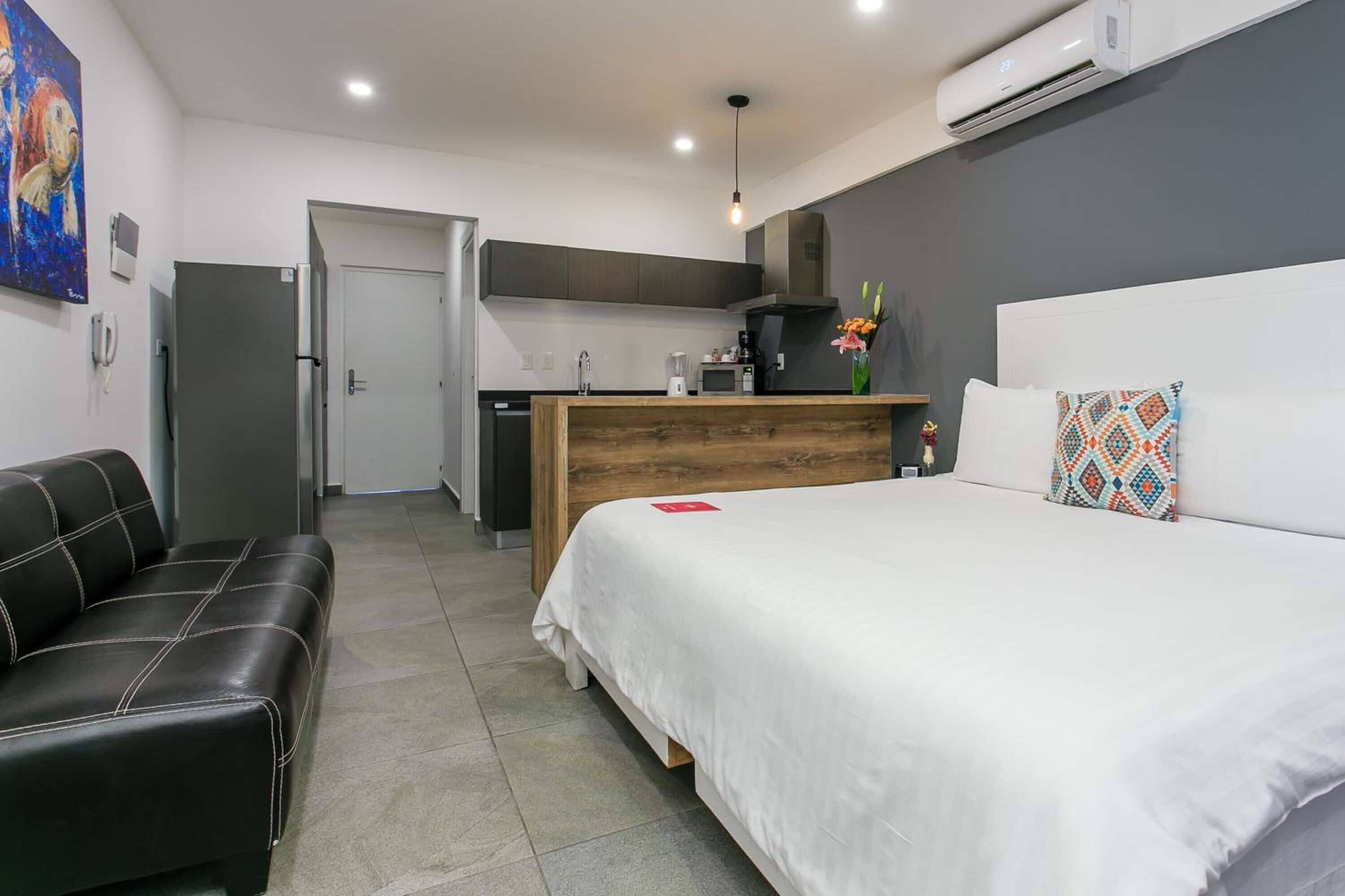Una habitación de hotel moderna con cama, sofá, kitchenette y baño.
