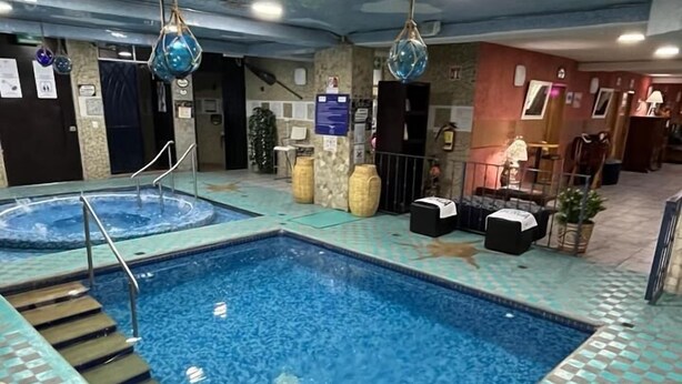 An indoor swimming pool with a checkered floor pattern, a hot tub, and a ceiling with a wave design. - Azul Turquesa Hotel Boutique (Cuernavaca)