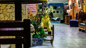A dining area with a table, a cup, a chair, a decorative horse statue, and a vase with flowers. - Azul Turquesa Hotel Boutique (Cuernavaca)