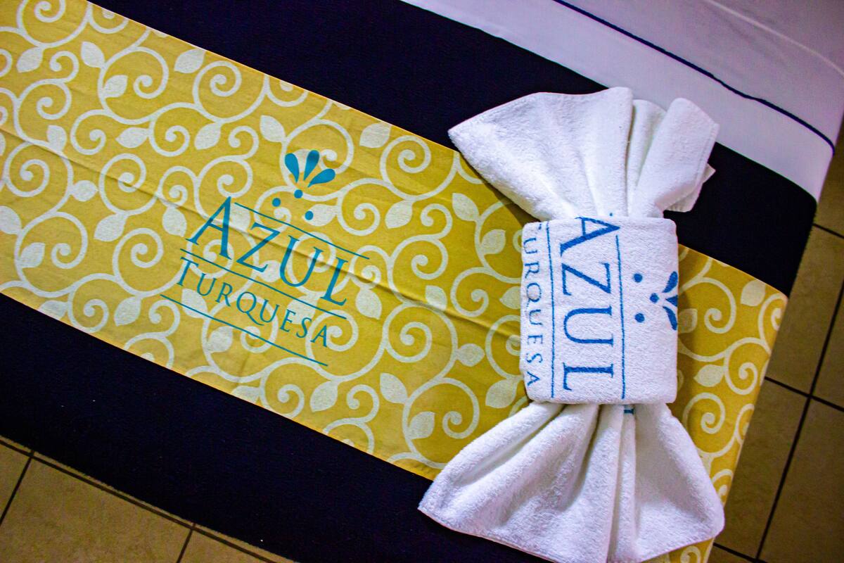 A towel tied around a yellow and white patterned hotel room card with the name "AZUL" visible.