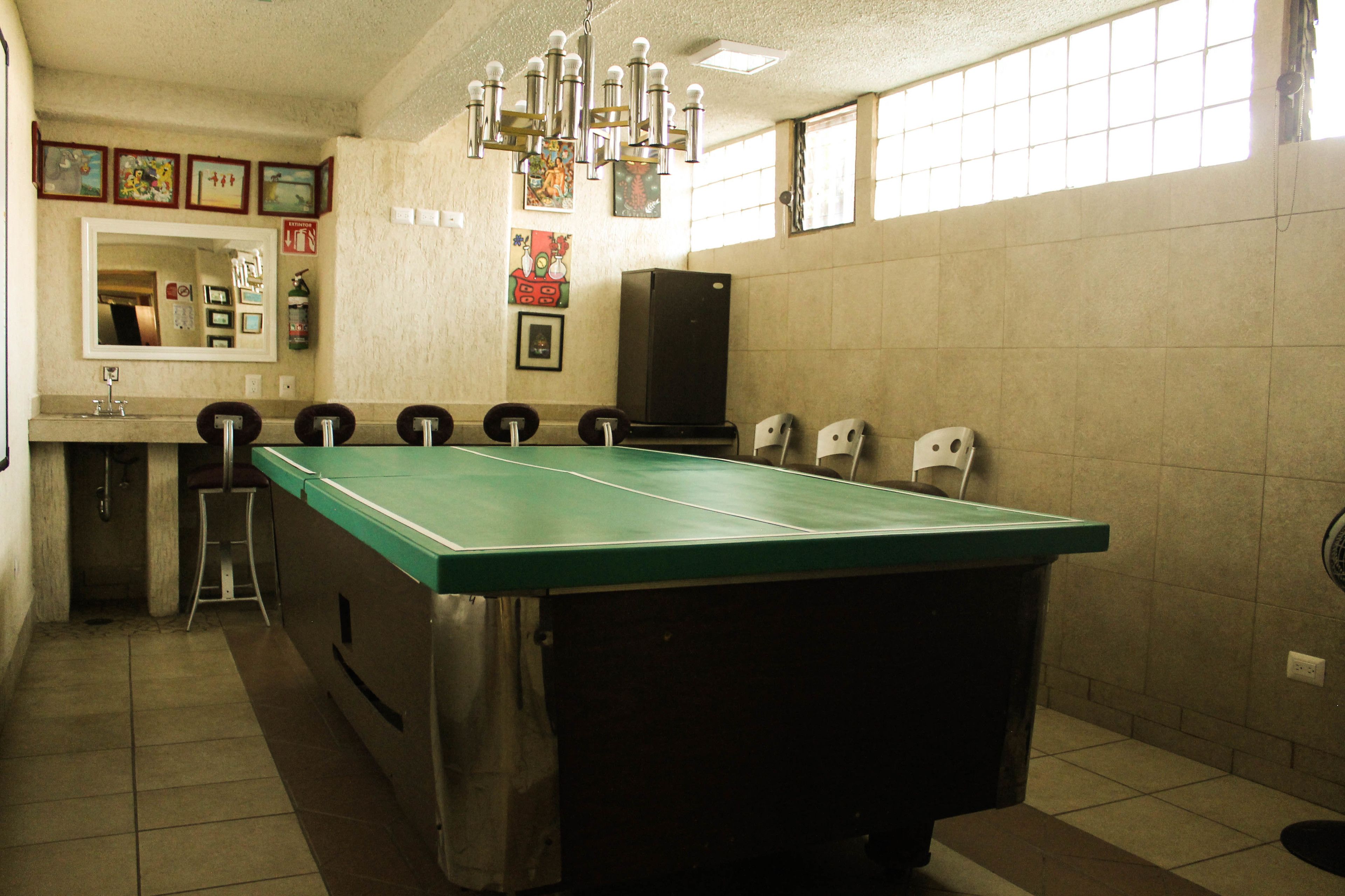 Une table de billard dans une pièce agrémentée d’un miroir, de tableaux encadrés et d’un haut-parleur.