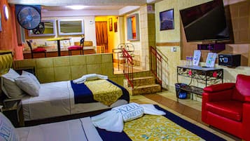 Een hotelkamer met twee bedden, een rode bank, een televisie en een bureau met een computer.