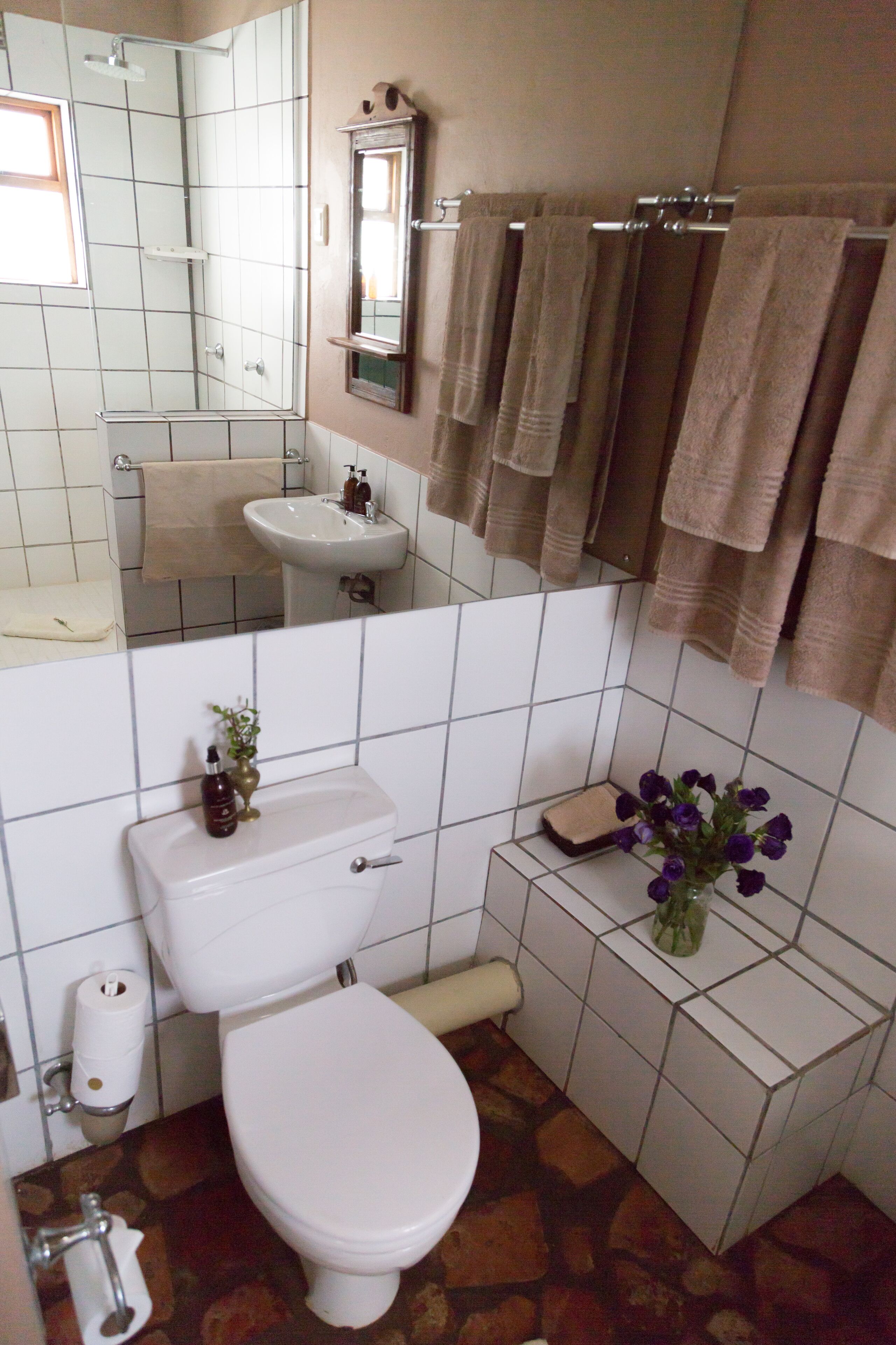 Kylpyhuone, jossa on wc, pesuallas, peili ja pyyhkeet.