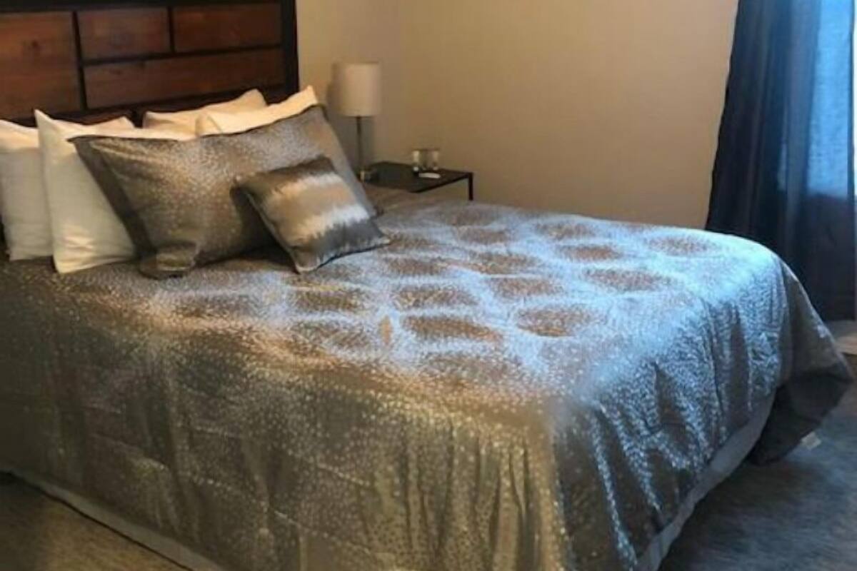 A neatly made bed with a patterned bedspread, a wooden headboard, and a bedside table with a lamp.