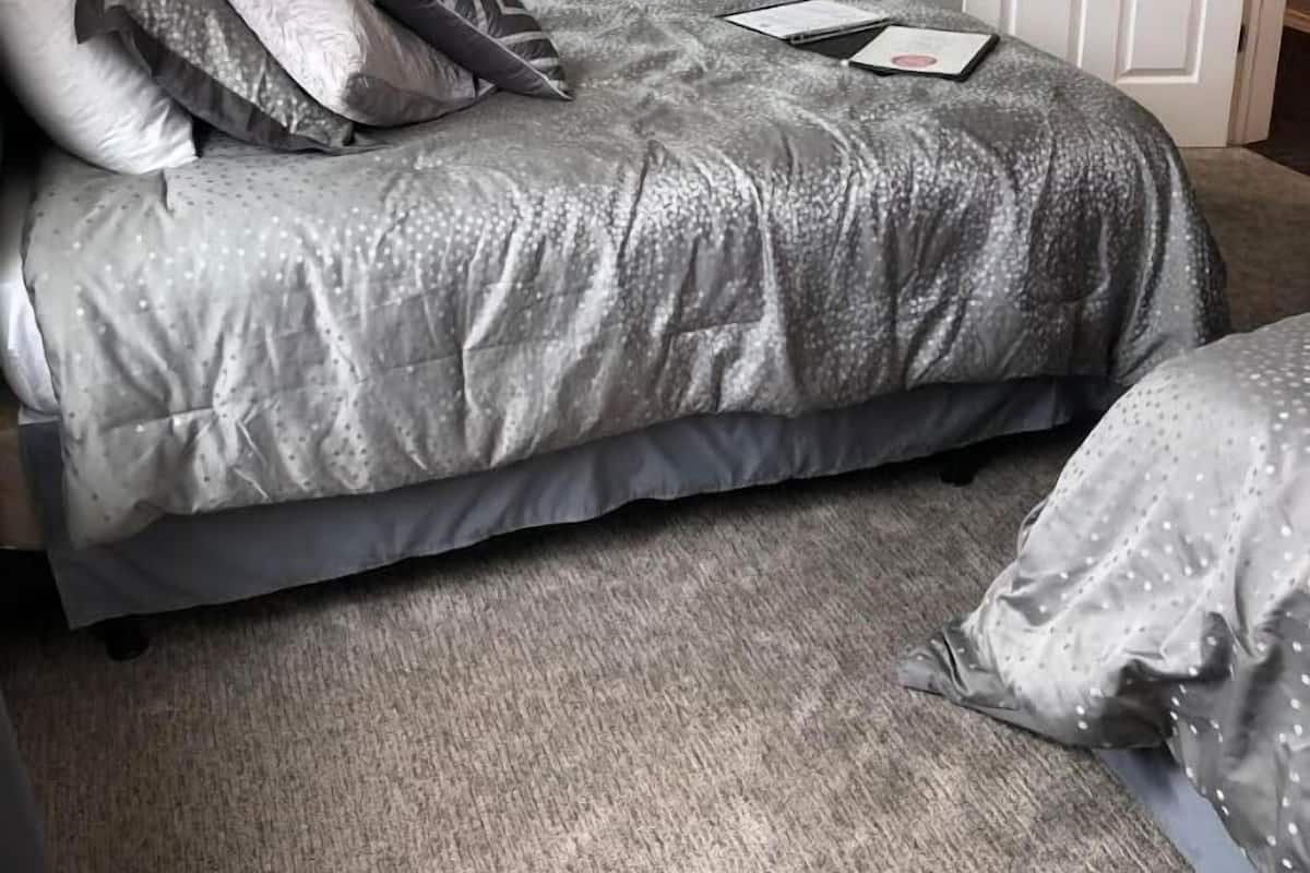 A bedroom with a large bed, a bedside table with lamps, and a door.