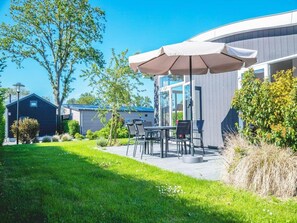 Un bâtiment moderne doté d’un patio aménagé avec des espaces de détente en plein air et un grand parasol.