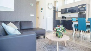 A modern living room with a sofa, a coffee table, and a dining area with chairs and a table. - Drenthe Family Getaway w/ Garden (West-Graftdijk)
