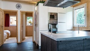 A modern kitchen with wooden cabinets, a built-in microwave, oven, and a large island with a sink.