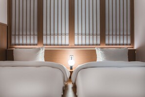 Une chambre d’hôtel avec deux lits, une tête de lit en bois et une table de chevet avec une lampe.