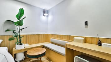 Relax in a serene space with a bench, table, and chair, surrounded by lush greenery and a stylish wooden accent wall.