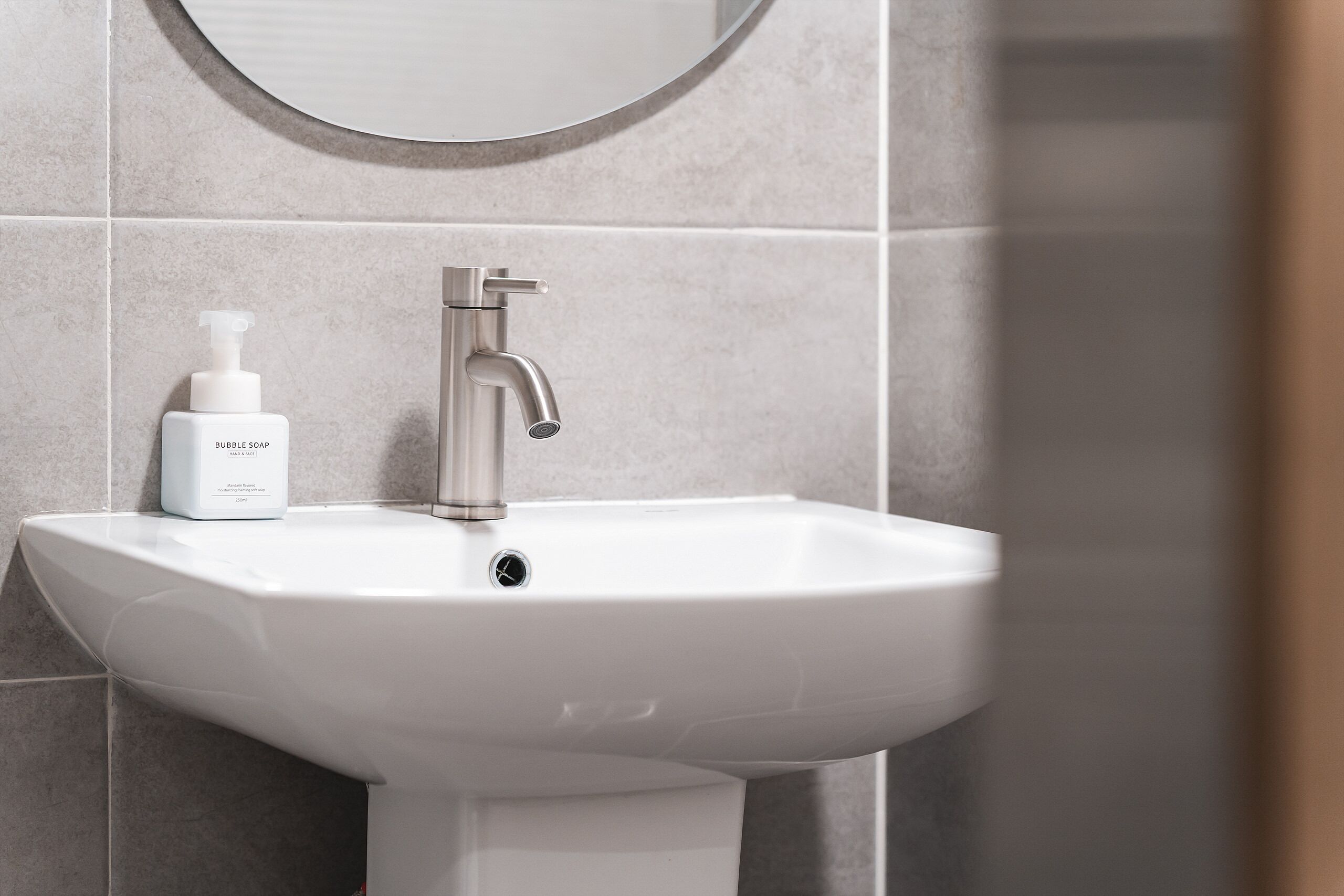 A bathroom sink with a modern faucet and a bottle of bubble soap.