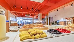 A buffet with various food items including bananas, olives, and a glass container of peanut butter.