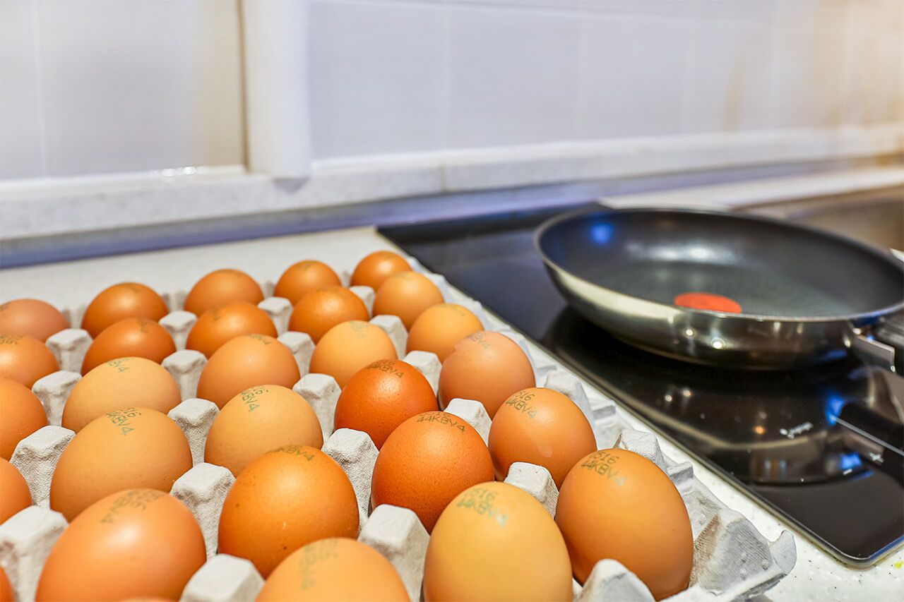 A carton of eggs next to a frying pan on a stove.