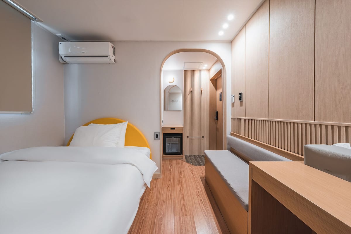Habitación de hotel compacta con cama, un pequeño rincón de descanso, kitchenette y armario.