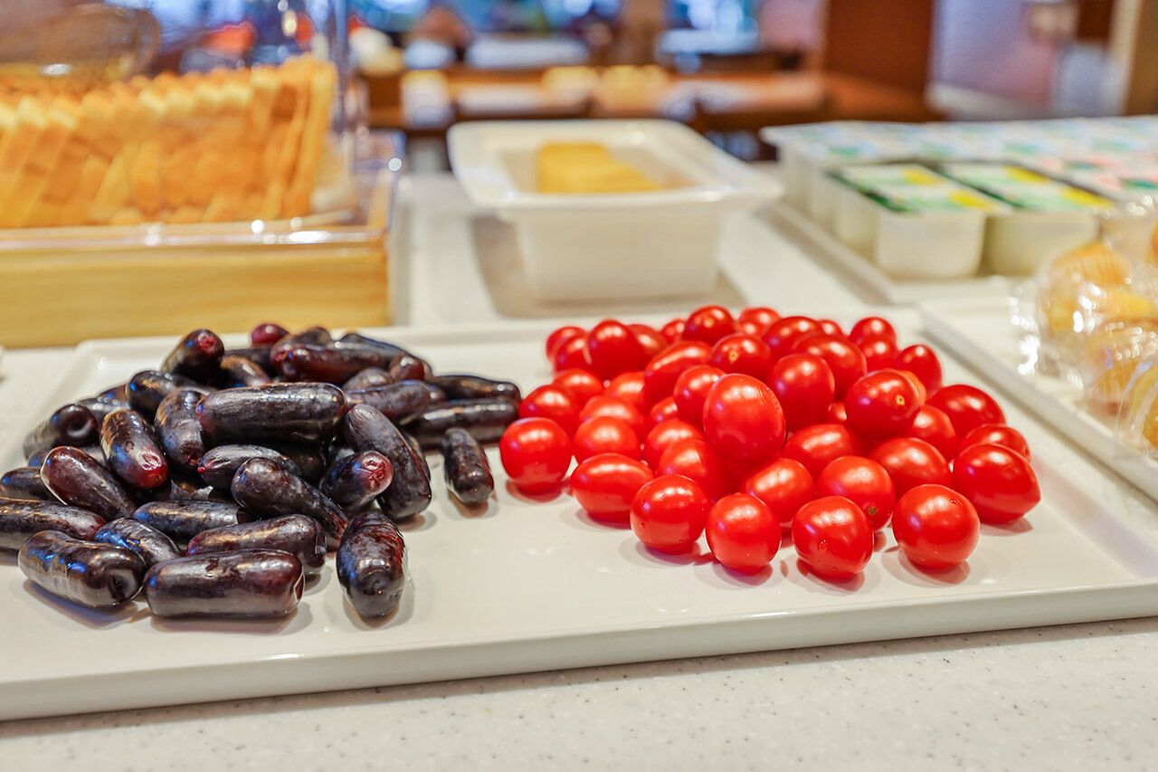 Buffet com diversos alimentos, incluindo salsichas e tomates cereja.
