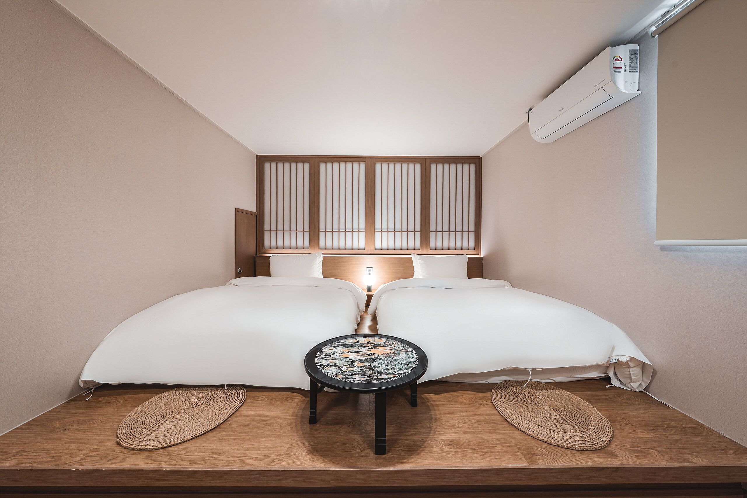 Une petite pièce agréable et confortable, avec un lit, une table de chevet et un climatiseur fixé au mur.