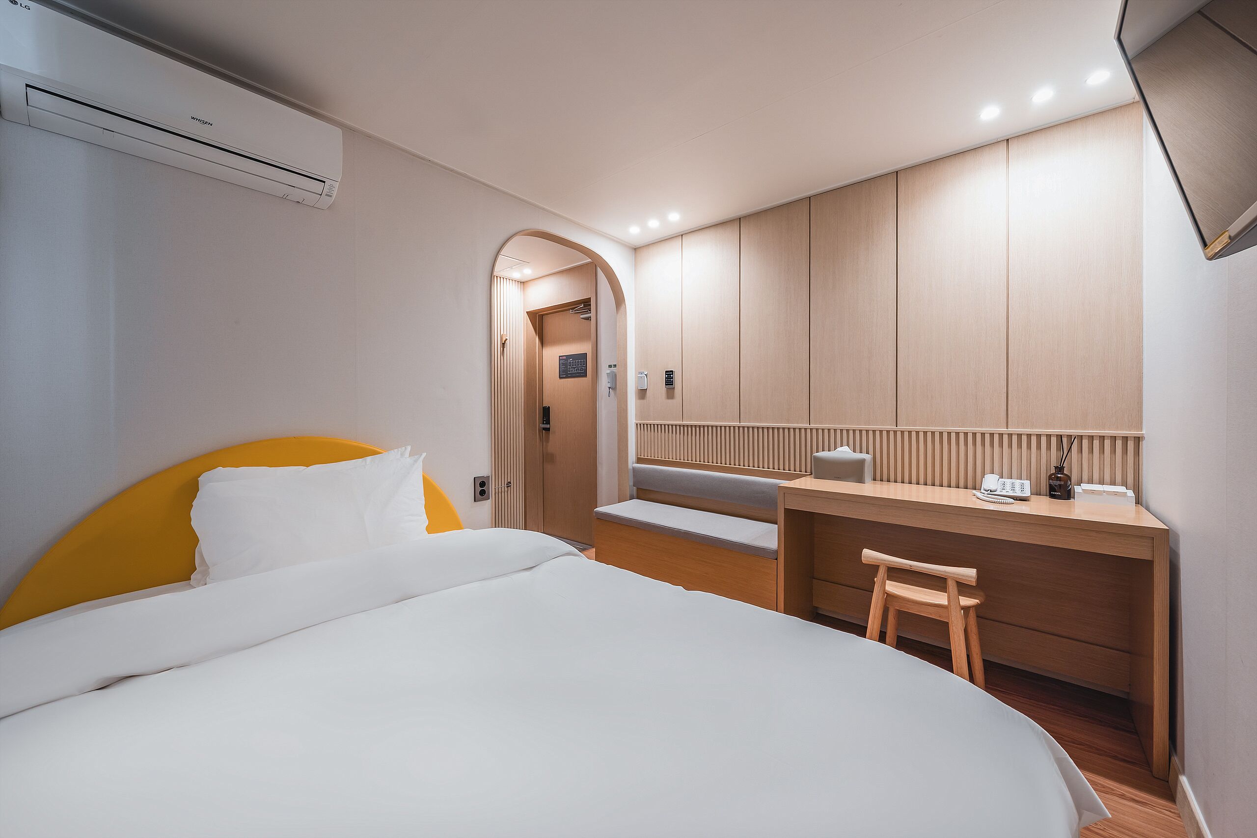 A modern hotel room with a bed, a desk, and a small seating area.