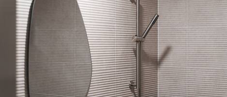 A modern bathroom with a shower, a large mirror, and a textured wall.