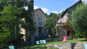 A stone building with a balcony, a swimming pool, and outdoor seating.