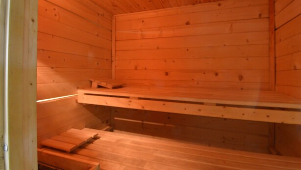 A sauna room with wooden walls and benches.