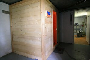 A wooden room with a door leading to a bathroom. - Charming holiday house with sauna, tanning bed, garden, terrace and lovely view (Nadrin)