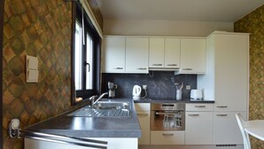 A compact kitchen with white cabinets, a built-in oven, and a sink.