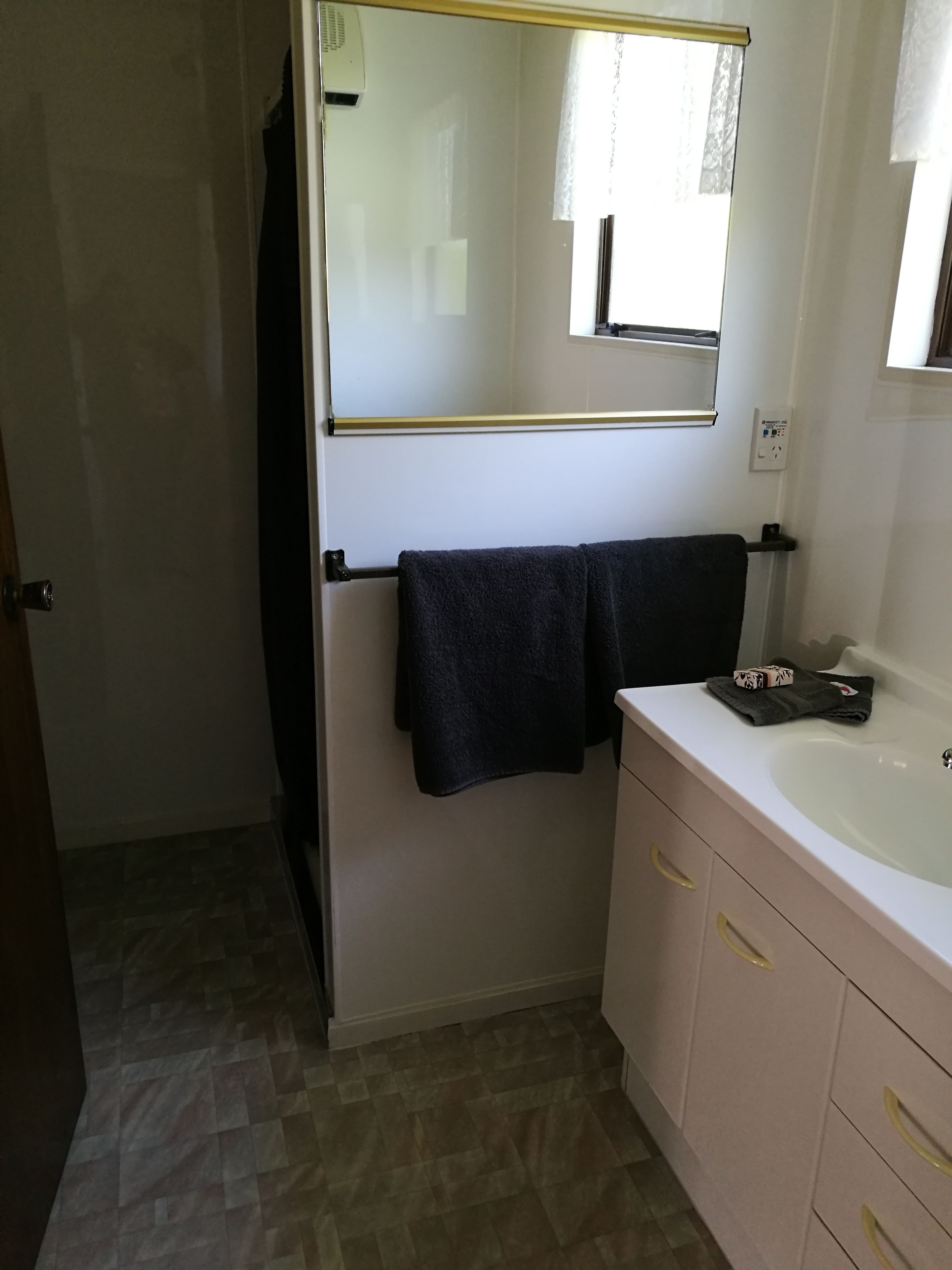A bathroom with a white sink, a mirror, a towel rack, and a door.