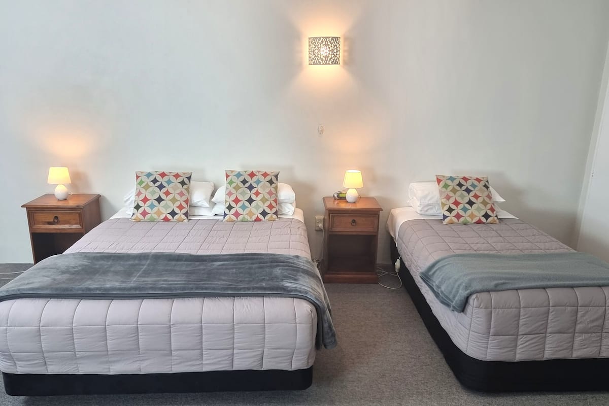 A double room with two beds, each with a bedside table and lamp, and a wall-mounted light fixture.