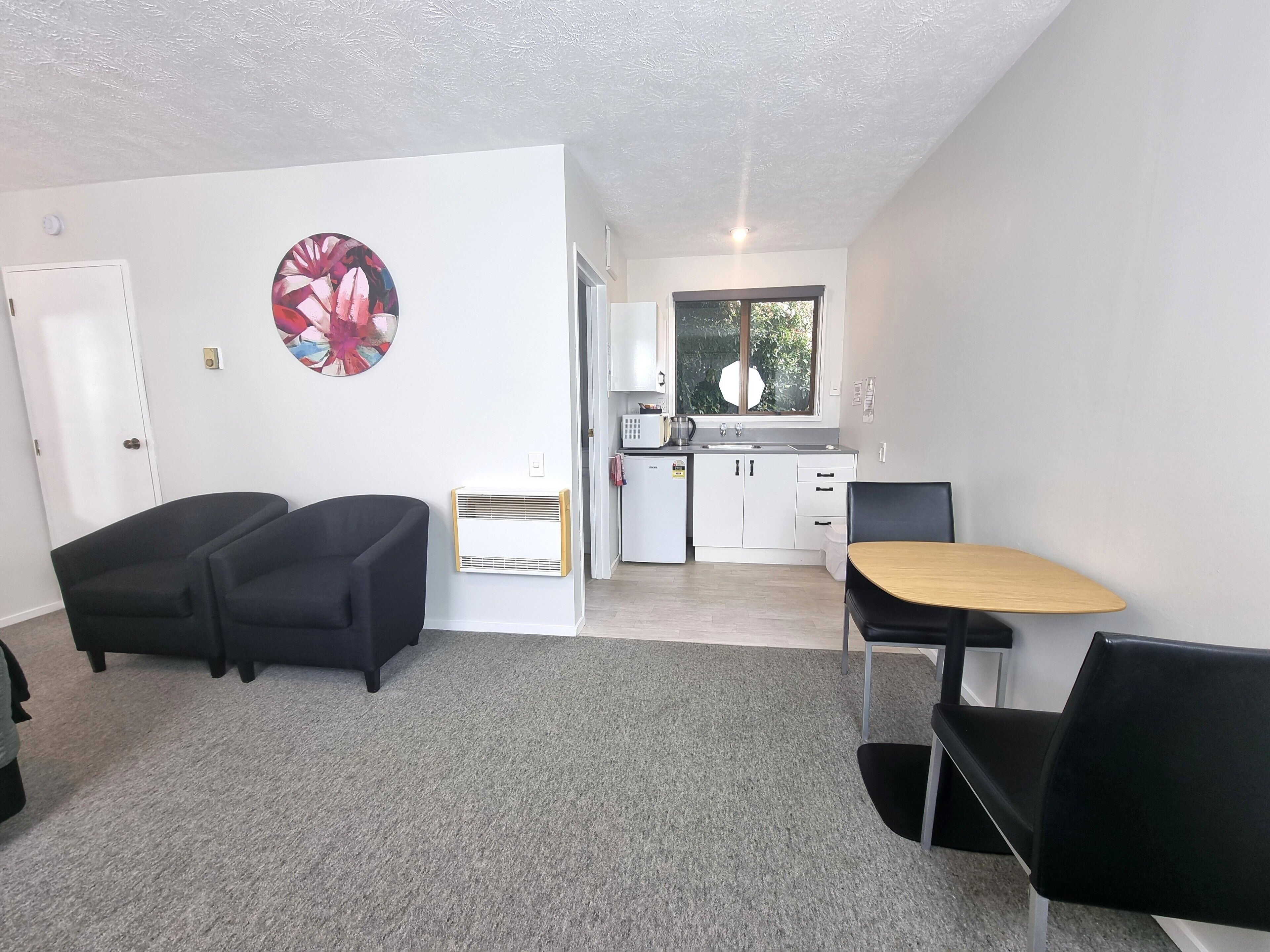 Un espacio habitable compacto con kitchenette, zona de comedor y sofá.
