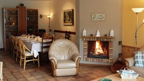 Zona de menjador amb una xemeneia, un sofà de cuir i una taula de dinar preparada per a quatre persones.
