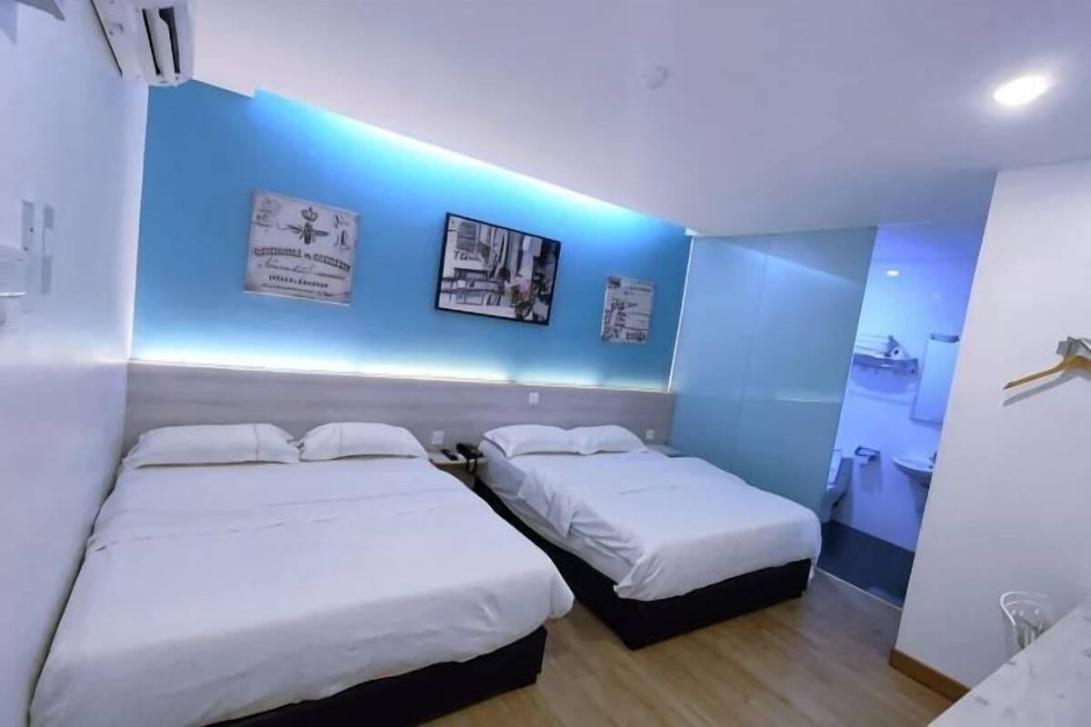 Una habitación de hotel con dos camas, un baño y una pequeña zona de estar.