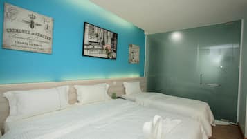 A hotel room with two beds, a teal accent wall, and a framed picture of a cityscape.