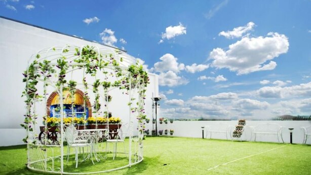 An outdoor wedding setup with a white arch and tables, a view of the sea, and a building in the background. - A Plus Boutique Hotel (Sekinchan)