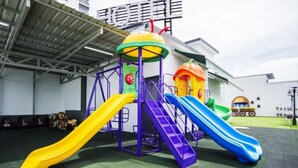 A playground with multiple slides and climbing structures, set against a building with a sign. - A Plus Boutique Hotel (Sekinchan)
