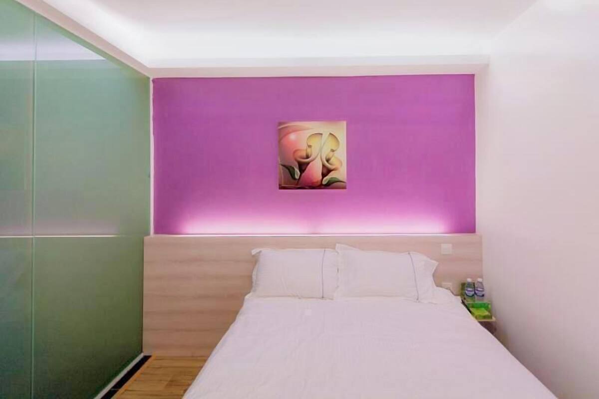 Un dormitorio con cama, mesita de noche, un cuadro en la pared y un armario verde.