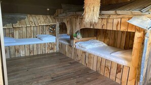 Una habitación rústica de madera con literas y una lámpara colgante de fibras tejidas.